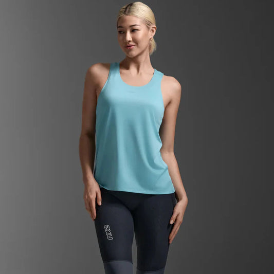Woman wearing a light blue tank top and black leggings on a gray background