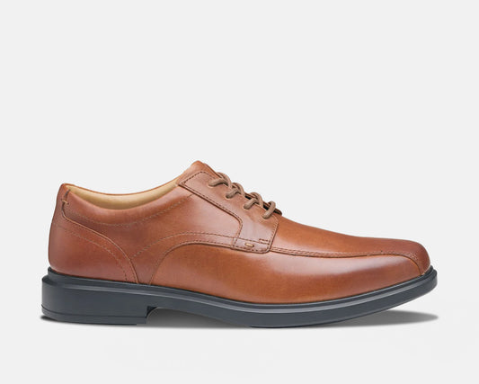 A tan, lace-up Oxford dress shoe with a low heel and rubber outsole.