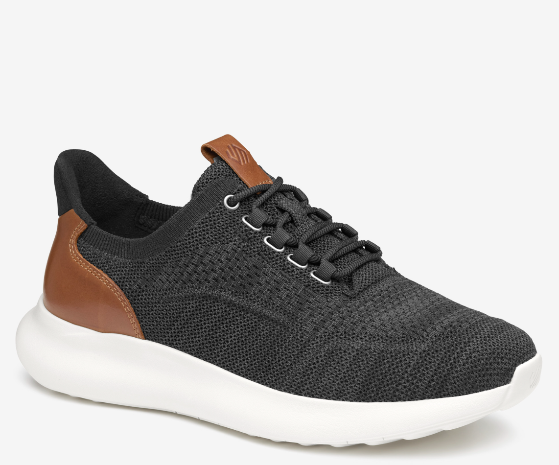 A pair of low-top athletic style knit sneakers with a plain toe design, featuring a black heathered knit fabric, brown leather trim, and a tan heel counter.